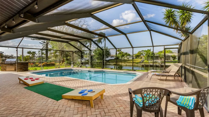 Villa Mahana - a pool area with a spacious pool and cornhole game - SWFL Vacation Rentals